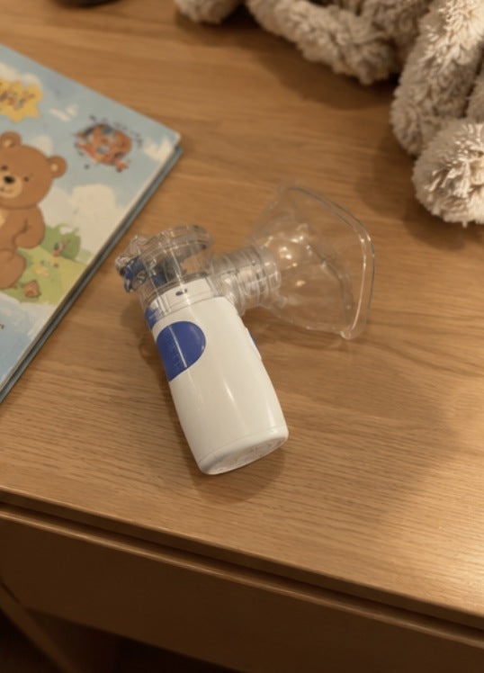 Portable nebuliser with a mask beside a children's book and teddy bear